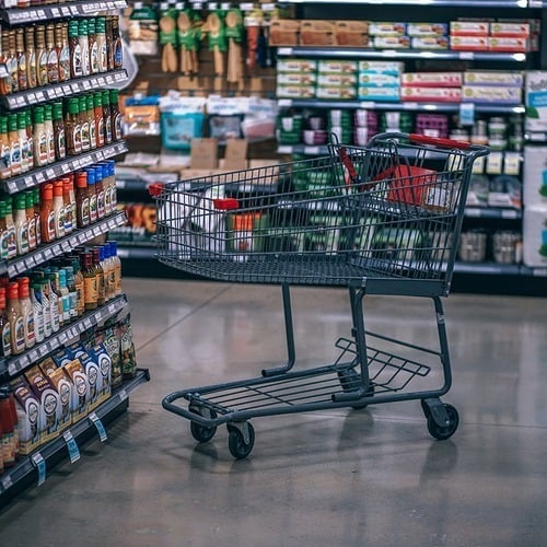 empty shopping trolley in the middle of a supermarket isle
