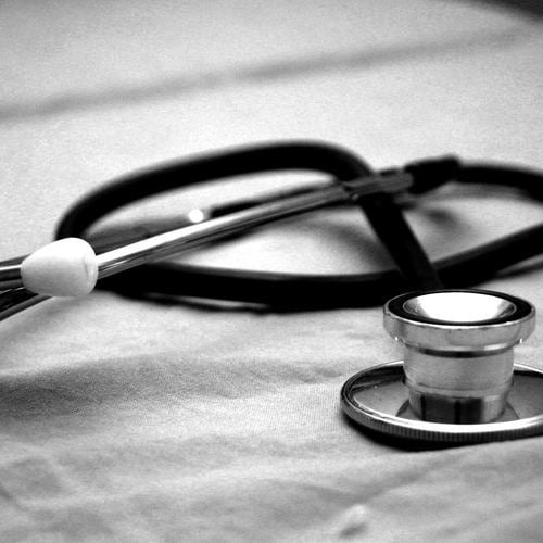 black and white image of stethoscopes on a bed sheet